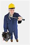 Portrait of mechanic with hammer carrying tool bag against white background