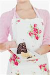 Woman in apron holding plate of tempting pastry over white background