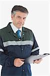 Portrait of mature repairman holding clipboard against white background