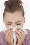 Closeup of woman blowing nose against white background