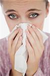 Portrait of unhappy young woman suffering from cold against white background