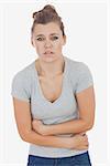 Portrait of young woman suffering from stomach ache against white background