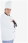 Portrait of mature chef in uniform standing with arms crossed against white background