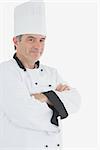 Portrait of male chef in uniform with arms crossed against white background
