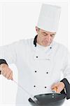 Male chef using spatula and frying pan over white background