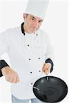 Portrait of mature chef with spatula and frying pan over white background