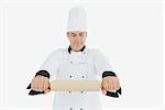 Male chef in uniform holding rolling pin over white background