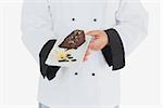 Chef offering garnished chocolate pastry over white background