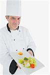 Portrait of male chef offering fresh prepared meal standing over white background