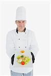 Portrait of male chef offering fresh meal standing over white background