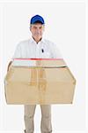 Portrait of courier man carrying cardboard box against white background