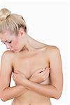 Naked young woman covering her breasts with hands over white background