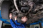 Male mechanic under car in garage