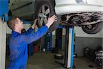 Auto mechanic examining car tire in garage