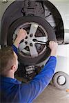 Male mechanic fixing car wheel in workshop