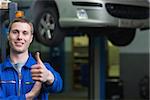 Portrait of confident auto mechanic gesturing thumbs up in workshop