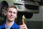 Portrait of car mechanic gesturing thumbs up in workshop