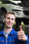 Portrait of handsome car mechanic gesturing thumbs