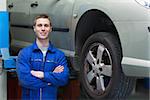 Portrait of male mechanic with arms crossed standing by car