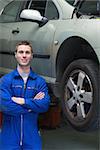 Portrait of happy male mechanic standing by car