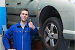 Portrait of male mechanic by car gesturing thumbs up