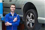 Portrait of male mechanic with spanner standing by car