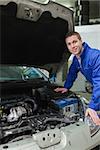 Portrait of happy male mechanic repairing car engine