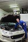 portrait of male mechanic by car giving thumbs up gesture