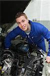 Portrait of confident male mechanic repairing car engine