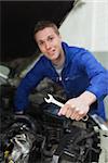 Portrait of male mechanic with spanner repairing car