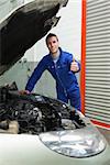 Portrait of auto mechanic by car gesturing thumbs up