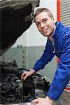 Portrait of male mechanic checking car engine oil