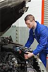 Male mechanic checking car battery in workshop