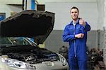 Portrait of male mechanic by car giving thumbs up gesture
