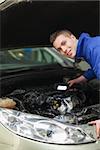 Portrait of repairman with flash light examining car engine