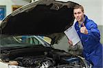 Portrait of male mechanic with clipboard gesturing thumbs up