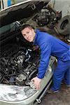 Portrait of male mechanic examining car engine