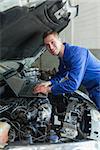 Portrait of repairman using laptop on car engine