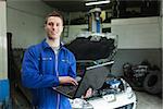 Portrait of auto mechanic working on laptop in workshop