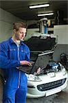 Male mechanic using laptop in auto repair shop