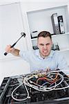 Portrait of frustrated young man hitting cpu with hammer at office