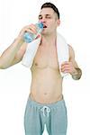 Portrait of young man drinking water with towel around neck over white background