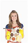 Portrait of smiling young maid holding wiper and disinfectant spray over white background