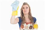 Beautiful young maid using duster and disinfectant spray over white background