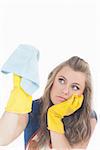 Bored young maid in yellow gloves using duster over white background