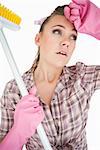 Tired young woman holding broom over white background