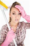 Portrait of tired young woman holding broom over white background