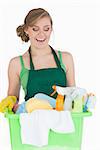 Happy young maid carrying cleaning supplies over white background