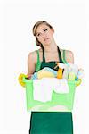 Tied young maid carrying cleaning supplies over white background