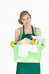 Portrait of tied young maid carrying cleaning supplies over white background